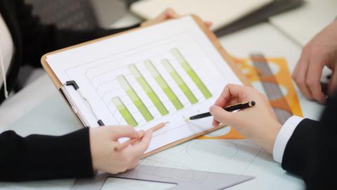 Group reviewing green bar charts on a clipboard